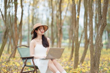 Kız ormanda dizüstü bilgisayar kullanıyor.