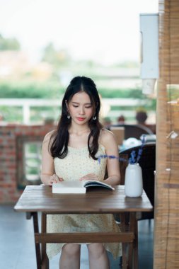 Kız bahçede kitap okuyor.