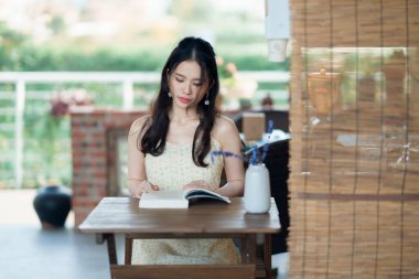 Kız bahçede kitap okuyor.