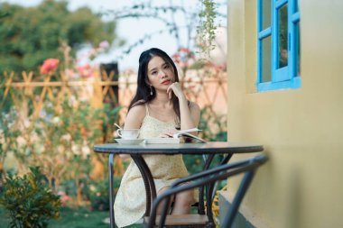 Kız bahçede kitap okuyor.