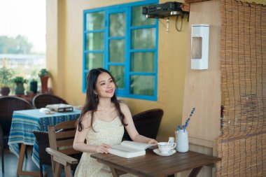 Kız bahçede kitap okuyor.