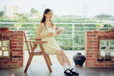 Kız bahçede kitap okuyor.