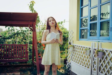 Kız bahçede kitap okuyor.