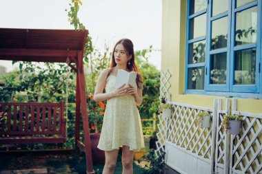 Kız bahçede kitap okuyor.