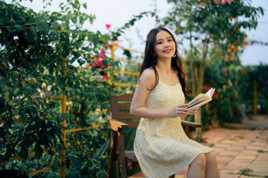 Kız bahçede kitap okuyor.