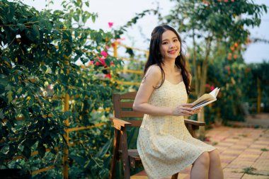 Kız bahçede kitap okuyor.