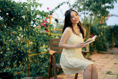 Kız bahçede kitap okuyor.
