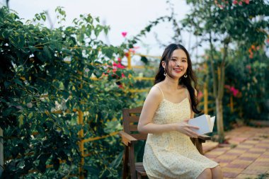 Kız bahçede kitap okuyor.