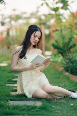 Kız bahçede kitap okuyor.