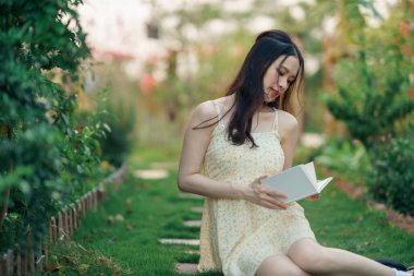 Kız bahçede kitap okuyor.