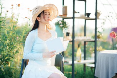 Genç kızlar bahçede kitap okurlar.