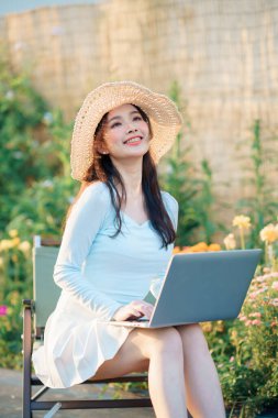 Genç kızlar bahçede dizüstü bilgisayar kullanır.