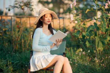 Genç kızlar bahçede kitap okurlar.