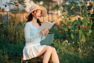 Genç kızlar bahçede kitap okurlar.