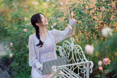 Genç kızlar bahçede dizüstü bilgisayar kullanır.