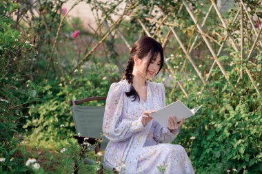 Genç kızlar bahçede kitap okurlar.