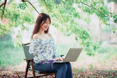 Kız ormanda dizüstü bilgisayar kullanıyor.