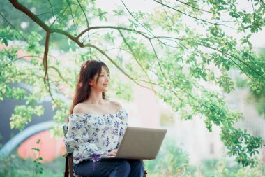 Kız ormanda dizüstü bilgisayar kullanıyor.