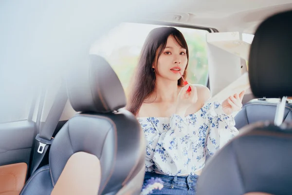 Fashionable Asian girls make up in the car