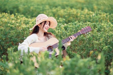 Kamp alanında gitar çalan bir kadın.