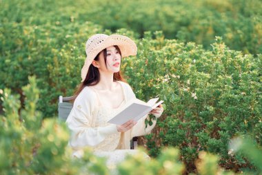 Kız parkta kitap okuyor.