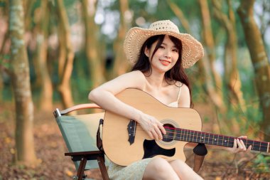 Kamp alanında gitar çalan bir kadın.