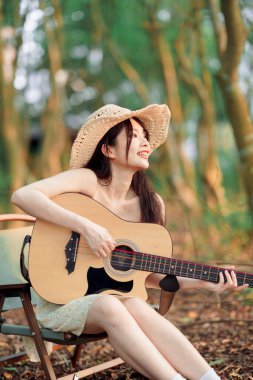 Kamp alanında gitar çalan bir kadın.