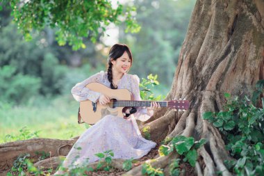 Kız banyan ağacının altında gitar çaldı.