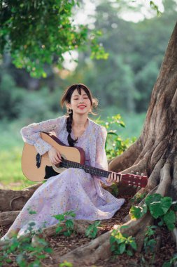 Kız banyan ağacının altında gitar çaldı.