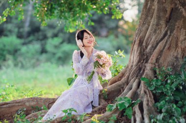 Kız banyan ağacının altında müzik dinledi.