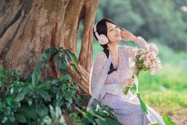 Kız banyan ağacının altında müzik dinledi.