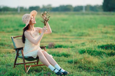 Moda kızı buketi çimlerin üzerinde tutuyor.