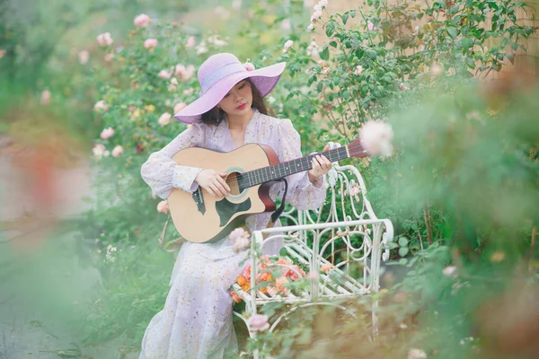 Fashion girl strumming guitar in the garden
