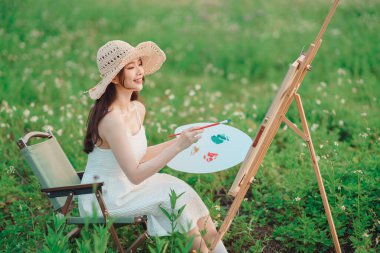 Kız çayırlarda çizim yapıyor.