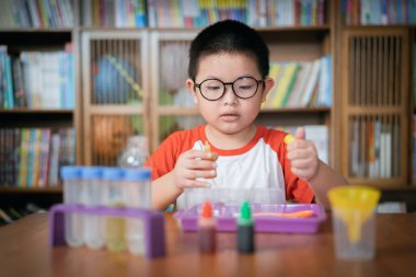 Küçük çocuk laboratuarda kimyasal deney yapıyor.