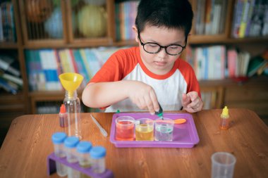 Küçük çocuk laboratuarda kimyasal deney yapıyor.