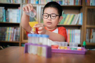 Küçük çocuk laboratuarda kimyasal deney yapıyor.