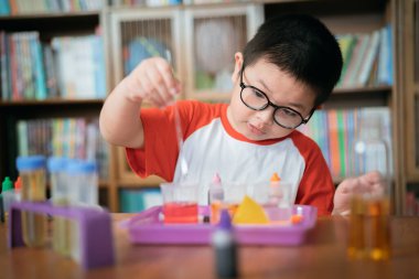 Küçük çocuk laboratuarda kimyasal deney yapıyor.