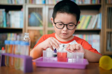 Küçük çocuk laboratuarda kimyasal deney yapıyor.