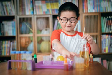 Küçük çocuk laboratuarda kimyasal deney yapıyor.