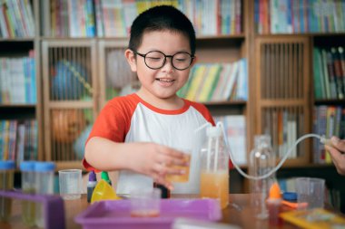 Küçük çocuk laboratuarda kimyasal deney yapıyor.