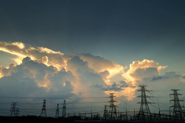 Elektrik iletim pilonu alacakaranlıkta mavi gökyüzüne karşı siluetlendi