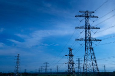 Elektrik iletim pilonu alacakaranlıkta mavi gökyüzüne karşı siluetlendi