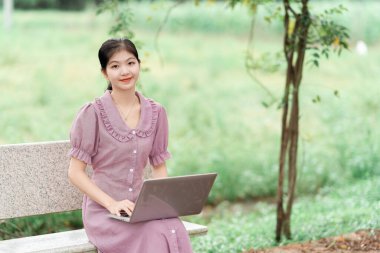 Güzel kız parktaki dizüstü bilgisayarı kullanıyor.