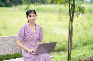 Güzel kız parktaki dizüstü bilgisayarı kullanıyor.