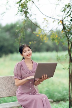Güzel kız parktaki dizüstü bilgisayarı kullanıyor.