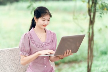 Güzel kız parktaki dizüstü bilgisayarı kullanıyor.