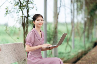 Güzel kız parktaki dizüstü bilgisayarı kullanıyor.