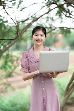 Güzel kız parktaki dizüstü bilgisayarı kullanıyor.