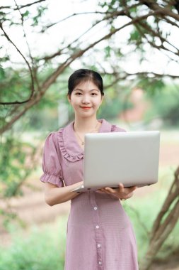 Güzel kız parktaki dizüstü bilgisayarı kullanıyor.